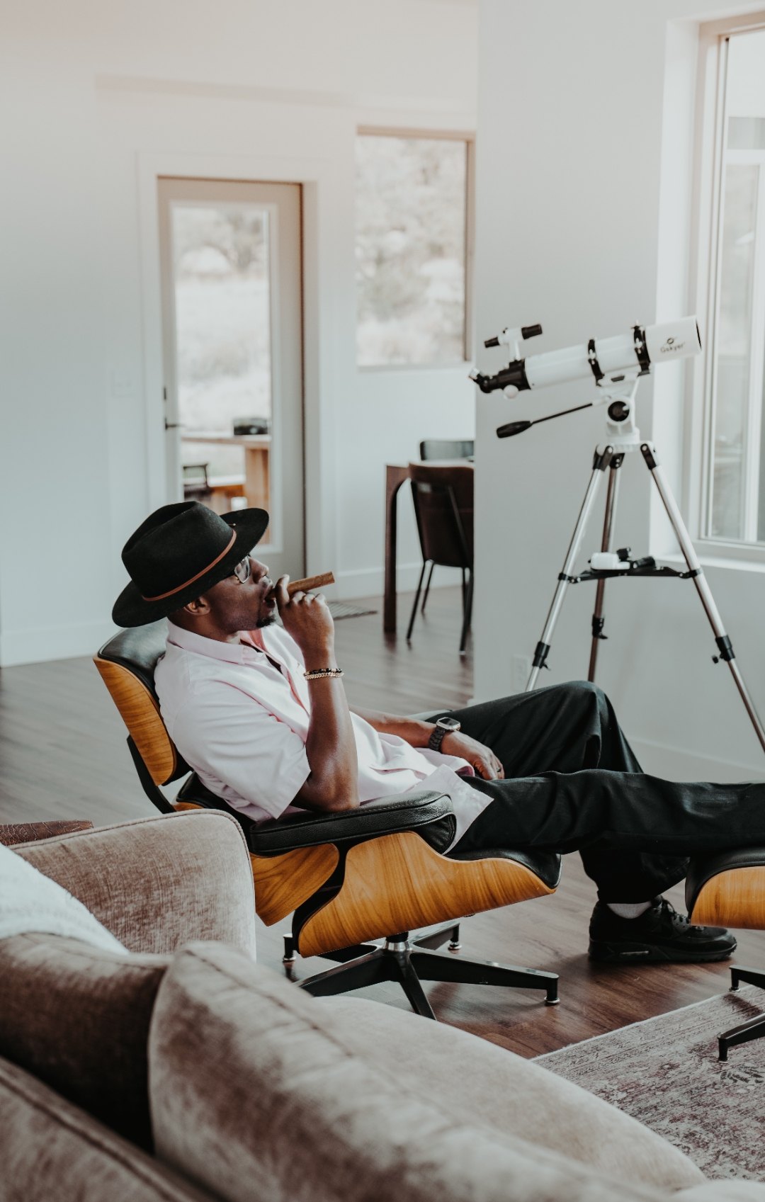 Ian Bennett reclined in a lounge chair beside a telescope in a bright desert house