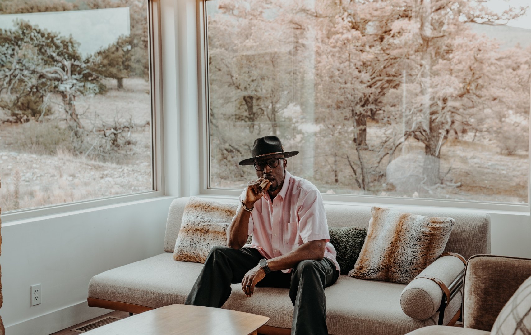 Ian Bennett seated on a linen sofa in front of a full wall of windows